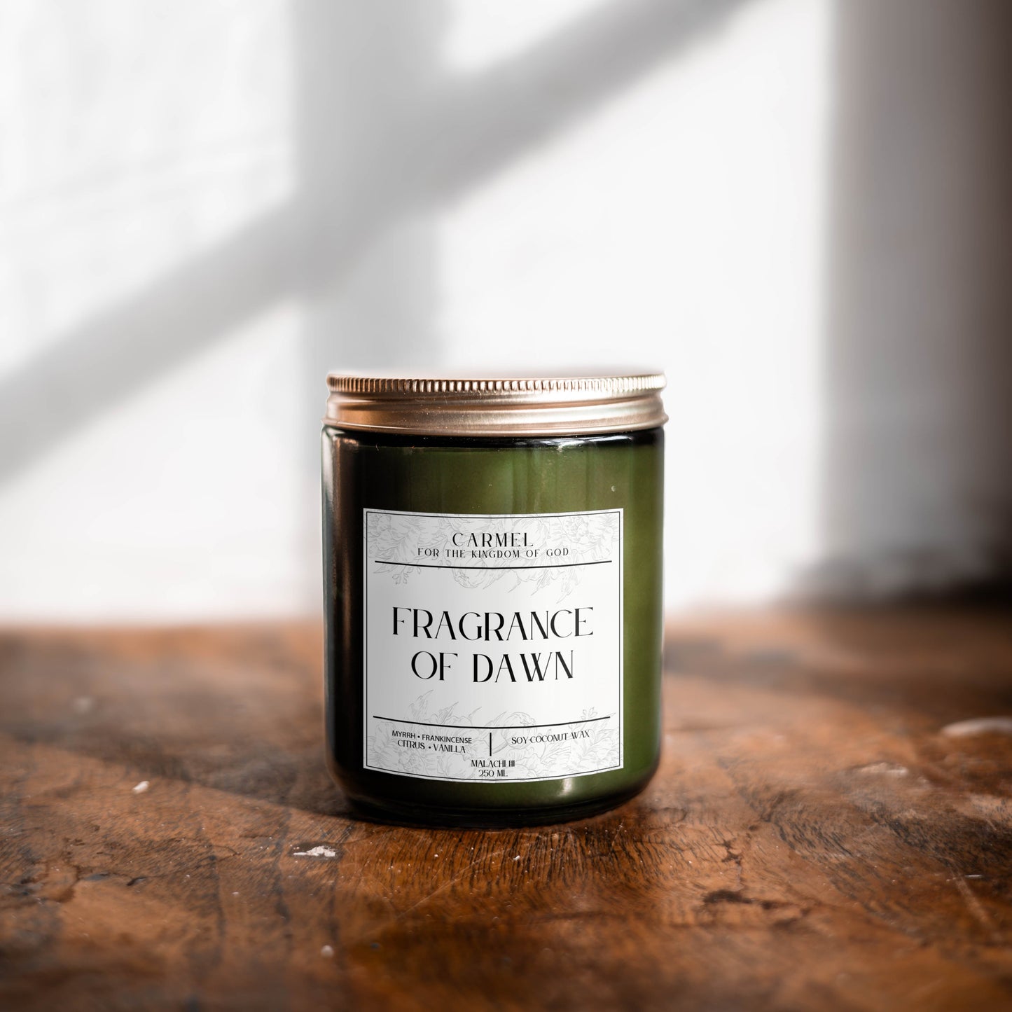 Candle labeled 'Fragrance of Dawn' on a wooden surface with a light background